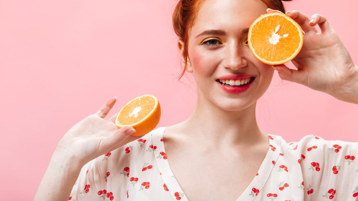 a woman holding two oranges up to her eyes